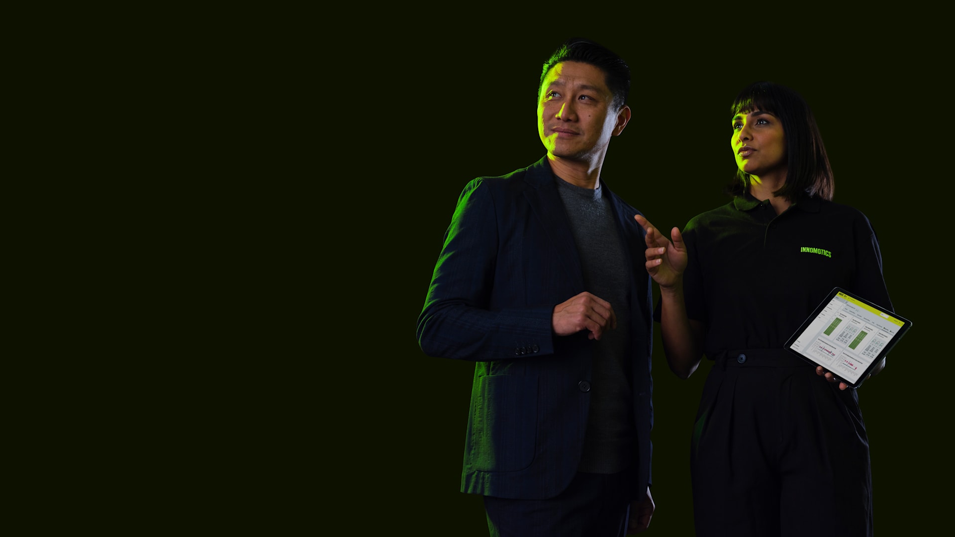 Business man and woman holding a tablet with Inspire IQ and looking towards something Business man and woman holding a tablet with Inspire IQ and looking towards something