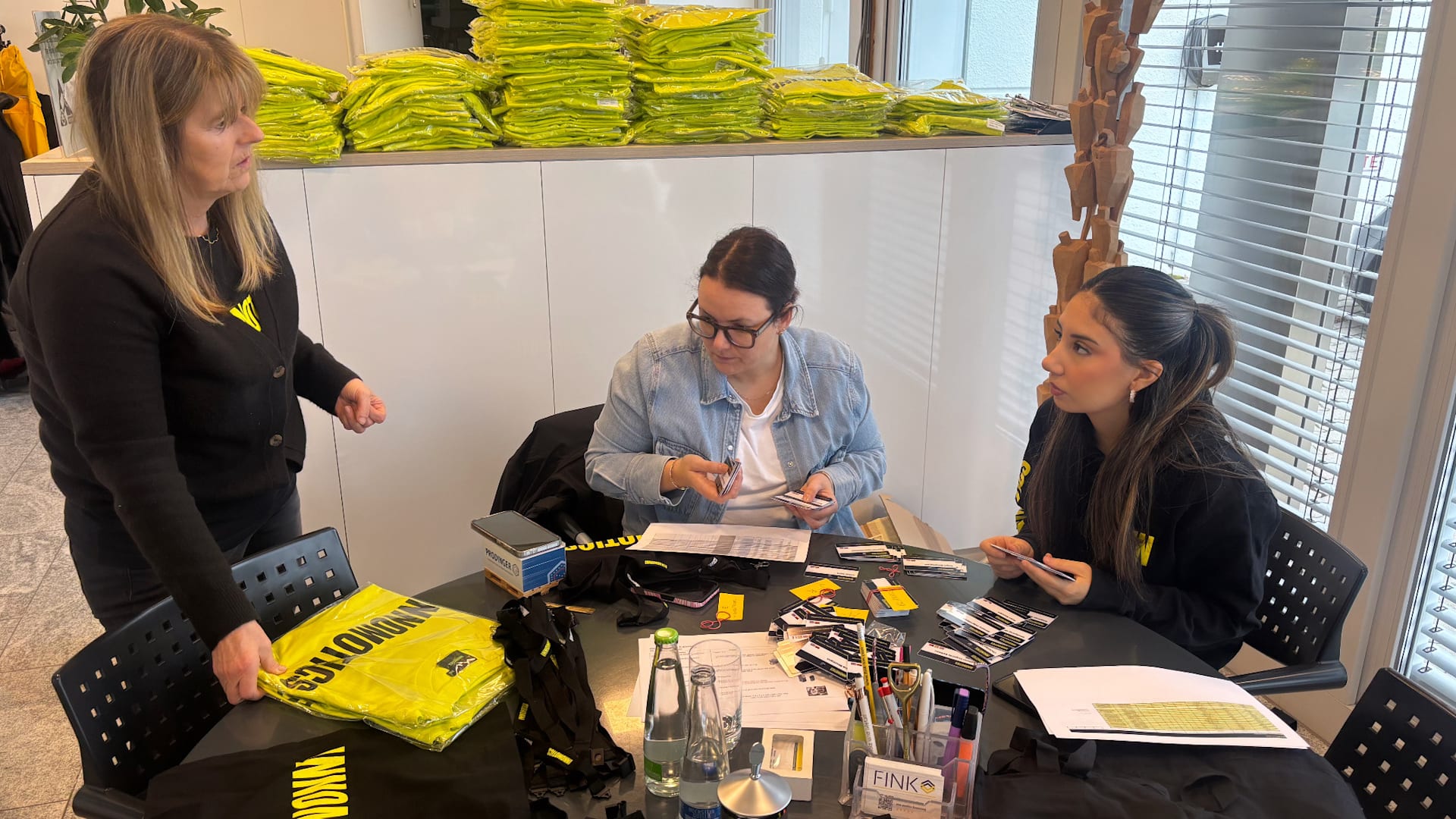 Three female colleagues around a table preparing merchandise for a tradeshow